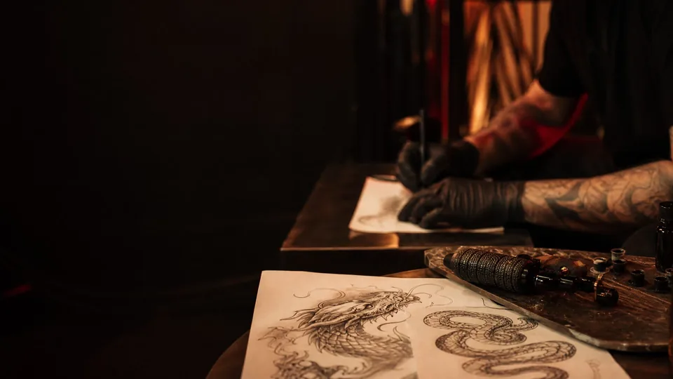 Processo criativo com desenho de dragão e máquina de tatuagem